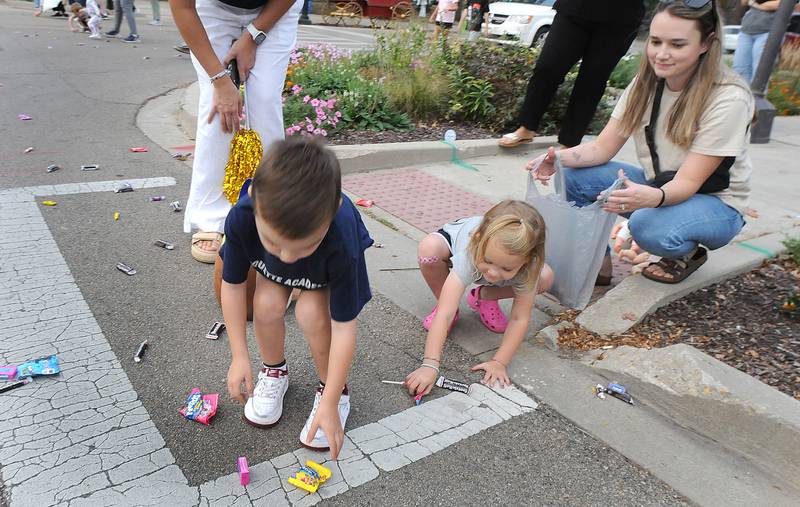 Children work to scoop up treats thrown their way during the Marquette Academy High Homecoming parade Wednesday in Ottawa.