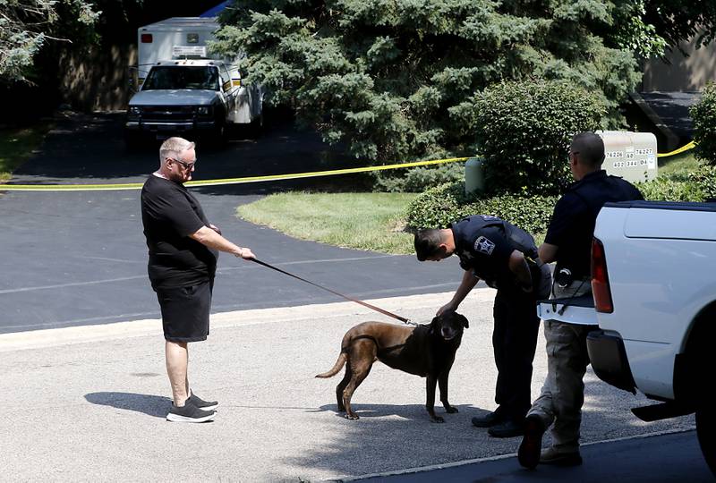 A neighbor and his dog stop to talk to McHenry County Sheriff deputies in the 5800 block of Wild Plum Road in unincorporated Crystal Lake on Thursday, Aug. 10, 2023, in front of a home where four family members, including three females and a male “aggressor,” were killed Wednesday.