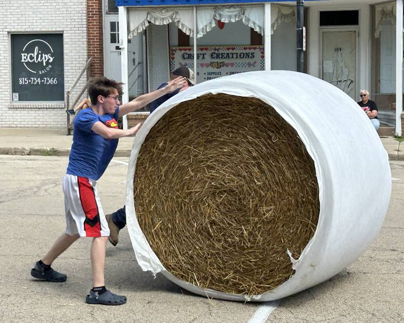 Sawyer Marceau of Polo and Zakkary West of Mt. Morris roll a large round straw bale down Wesley Avenue and across the finish line in Mt. Morris during the Straw Bale Race at Strawfest on Saturday, Aug. 23, 2025. The 17-year-olds won the event with the fastest time of 9.36 seconds.