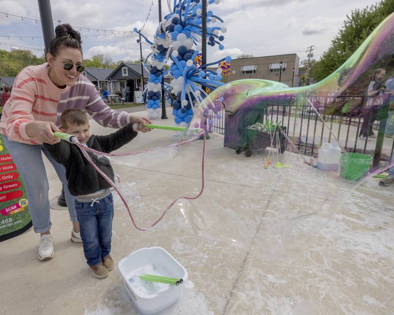 Jillian Sparks and her son James play with the bubble making station that was part of the grand opening event for Market On Mill on May 3, 2025 in Utica, Illinois.