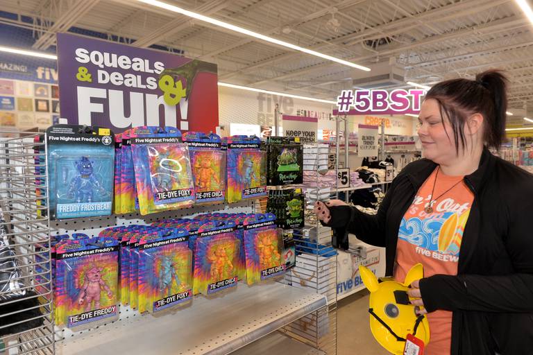 Erin Sucher, manager of Five Below, shows some of the trending merchandise offered by the new store on Thursday, Oct. 12, 2023 at the Sterling Crossings retail center,