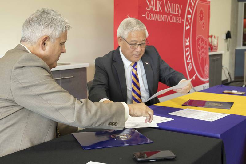 Sauk Valley Community College President Dave Hellmich signs an agreement with Western Illinois University President Guiyou Huang to help address the teacher shortage.
