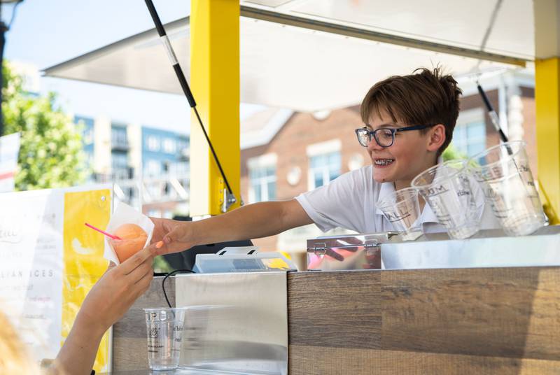 Michael, 13, serves Italian ice at the Chill’s Italian Ice food truck during Make Music Wheaton and the Wheaton French Market in The Wheaton French Market Plaza on Saturday, June 21, 2025.