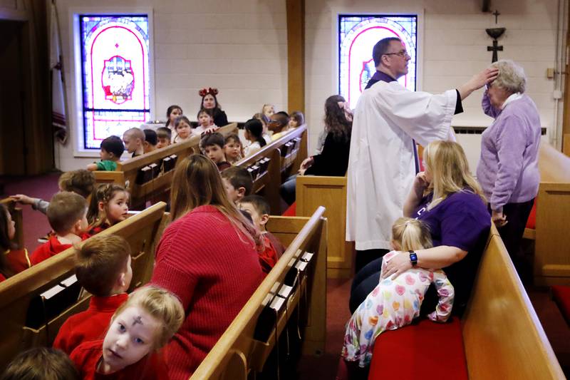 Rev. Mark Buetow, of the Zion Evangelical Lutheran Church in McHenry, places ashes on a church member on Wednesday, Feb, 14, 2024, during a service for the students and church members on Ash Wednesday.