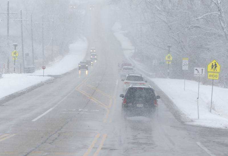 Cars traverse limited visibility and wet roads as they travel on Walkup Road near Prairie Ridge High School on Wednesday, Jan. 25, 2023. Snow fell throughout the morning, leaving a fresh blanket of snow in McHenry County.