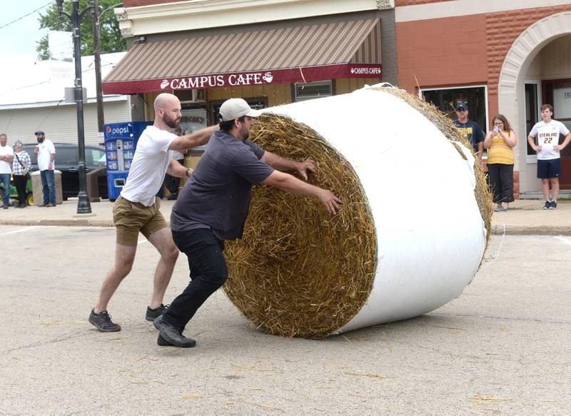 Seth Larson of Shorewood and Alex Phillips of Monee roll a large hay bale down Wesley Avenue in Mt. Morris during StrawFest on Saturday, Aug. 26, 2023. The bale rolling was one of the activities. The pair won the event in 10.89 seconds.