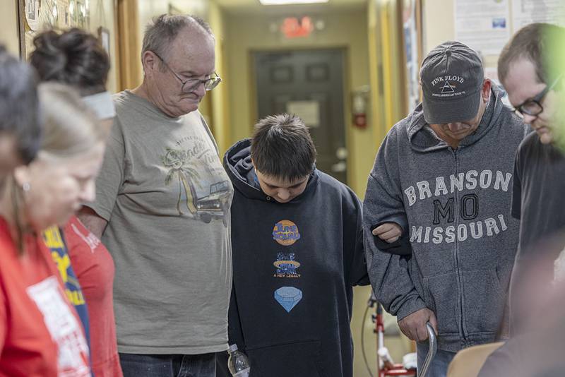 Clients bow their heads and join hands in prayer Wednesday, Jan. 7, 2026, at the Sterling PADS shelter before dinner is served. The shelter is seeing huge numbers of people utilizing the facility.