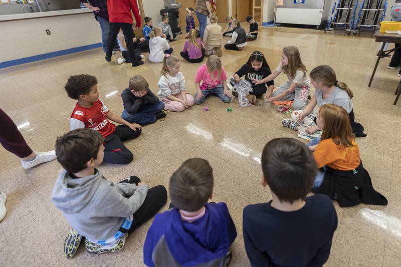 Third graders sit in a circle and unwrap a ball of plastic wrap Tuesday, Jan. 30, 2024 at St. Anne’s school for a fun activity in celebration of Catholic Schools Week.