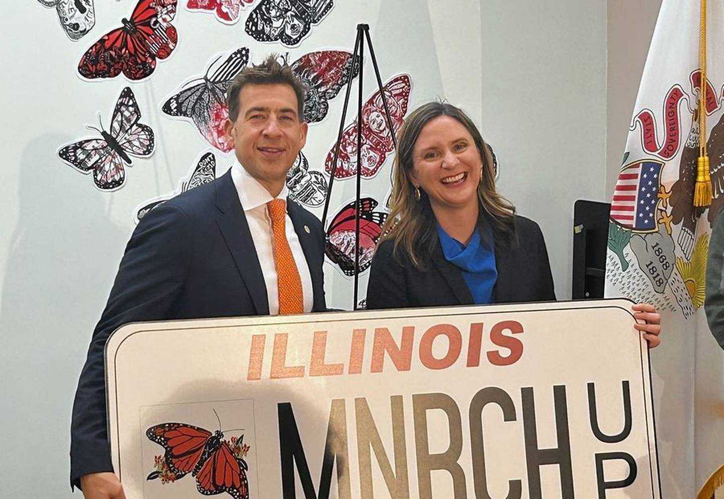 Secretary of State Alexi Giannoulias and Illinois Environmental Council Executive Director Jen Walling hold up a large version of the state's new specialty monarch butterfly license plate at an unveiling event Nov. 16, 2023.