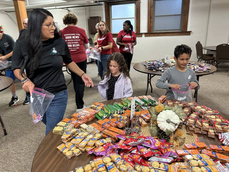 John and Eliana Murphy, ages 5 and 7, and their mom Michelle, fill care packages headed for sailors on the USS Fitzgerald at the Evangelical Free Church of Mt. Morris  on Thursday, Oct. 16, 2025. Michelle's husband, and John and Elaine's dad, Logan, is the chaplain on the destroyer and was an associate pastor at the Mt. Morris church.