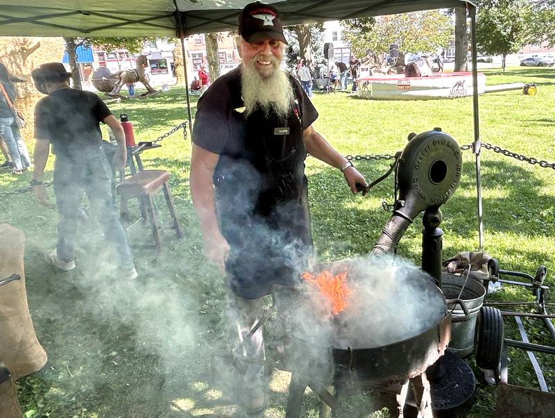 Blacksmith Lloyd Bellows of Oregon stokes the fire at Strawfest on Saturday, Aug. 23, 2025 on the Campus square in downtown Mt. Morris. Visitors could watch Bellows make a variety of iron objects during the event.