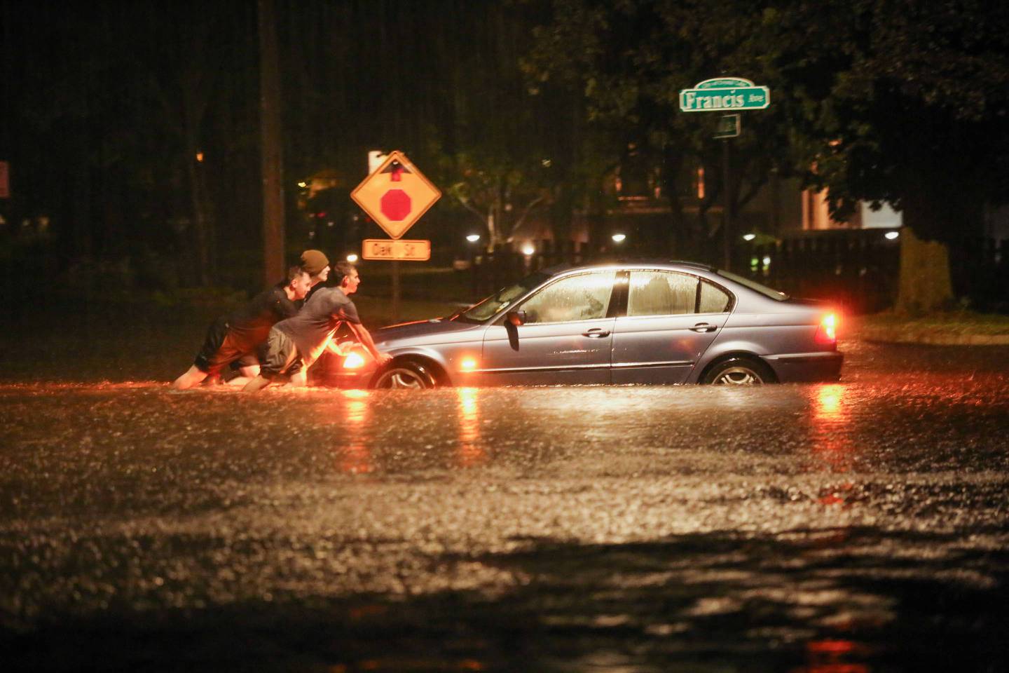 People push a stuck car on Crystal Lake Avenue and Francis Avenue in Crystal Lake during Friday night storms.