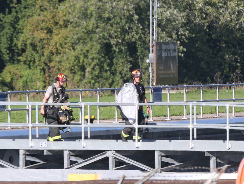 Utica firefighters James Didrickesn and Koty Gapinski walk across the Starved Rock Lock and Dam to leave the scene of a fire inside the Starved Rock hydroelectric power plant on Tuesday, Oct. 3, 2023 in Utica.