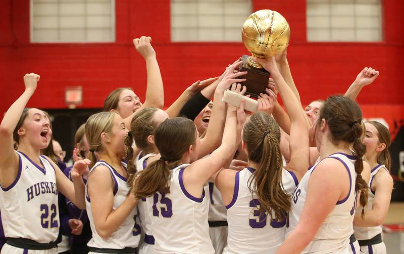 Members of the Serena Lady Huskers basketball team hoist the Little Ten Conference championship trophy after beating Hinckley-Big Rock on Friday, Jan. 24, 2025 at Earlville High School.