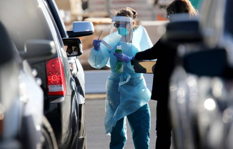 A Northwestern Medicine Immediate Care McHenry employee collects a sample from a person in line Monday with a doctor's order for a COVID-19 test at Northwestern Medicine Immediate Care McHenry on North Richmond Road in McHenry.