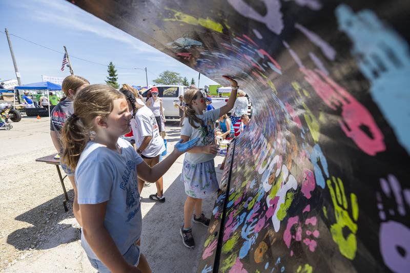 Taking things literally at Rock Falls' Touch-a-Truck event, Anna Day (left), 7, and Maddy Velazquez, 8, of Walnut plant their hand prints on a truck Saturday, June 28, 2025, in Rock Falls.