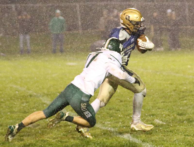 Marquette's Grant Dose runs the ball in the pouring rain while St. Bede's Ryan Nawa brings him down on Friday, Oct. 13, 2023 at Gould Stadium.