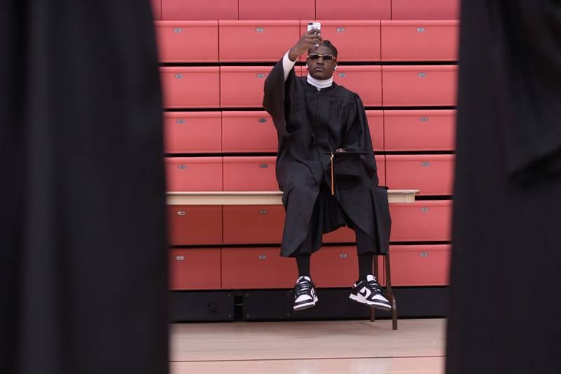 Marion Taylor takes a selfie while sitting on a table before the start of the DeKalb High School graduation ceremony at the Convocation Center in DeKalb on Saturday, May 28, 2022.
