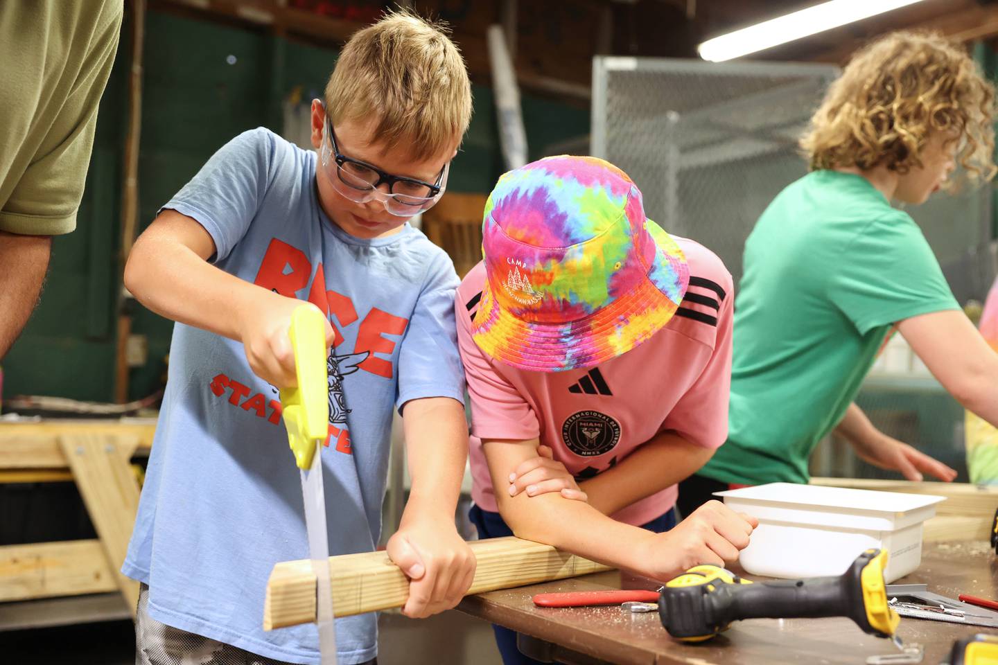 Kevin Donnelly, left, 10, of Oak Brook, works to cut a V-notch in a piece of wood as fellow camper Liam Adrichik, also 10, of Naperville, helps hold the board steady during Tool Time at Camp Shaw-Waw-Nas-See on Wednesday, July 16, 2025.