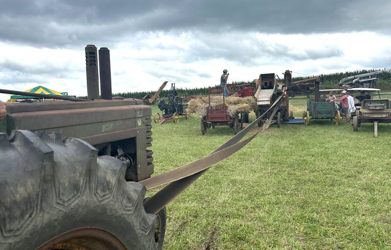 An antique tractor powers a threshing machine with a belt and pulley at the Bos Brothers Historical Farm south of Erie on Saturday, July 26, 2025. This year's event focused on harvesting wheat.