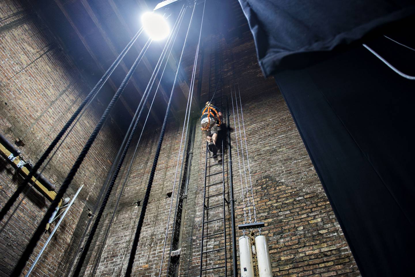 Lead technician Scott Shipp climbs to the top of the building to work on the new fly system.