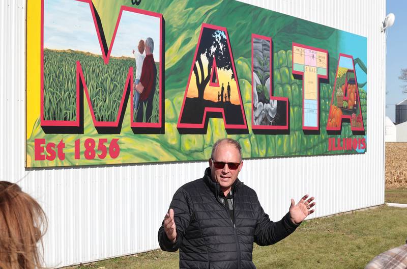 Malta Village President Bob Iverson talks about the new mural by Dixon artist Nora Balayti before the official ribbon cutting Wednesday, Oct. 19, 2022, on the north side of Route 38 in Malta. The mural, which spells out Malta in large capital letters, depicts the values of the town with themes of agriculture, family, community and growth.