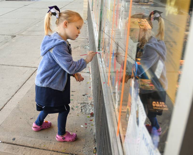 Addy Orf, 5 years old, of Downers Grove paints a window during the Halloween Window painting event held Downtown Downers Grove on Saturday Oct. 21, 2023.