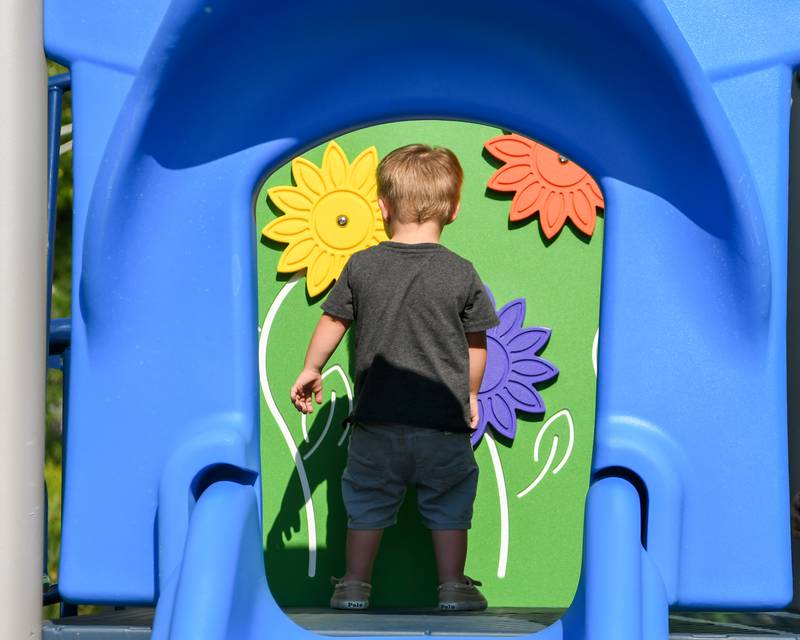 Teddy Clarke, 2, of Elburn enjoys spinning interactive flowers on the new playground during the dedication on Saturday Aug. 16, 2025, held at Prairie Park in Elburn.