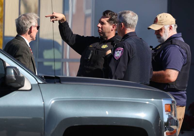 Law enforcement officers talk to DeKalb City Manager Bill Nicklas Wednesday, Oct. 23, 2024, outside of the Brian Bemis Toyota car dealership in DeKalb after responding to a stabbing where multiple employees were injured. The incident ended after police shot the man wielding the knife authorities said.
