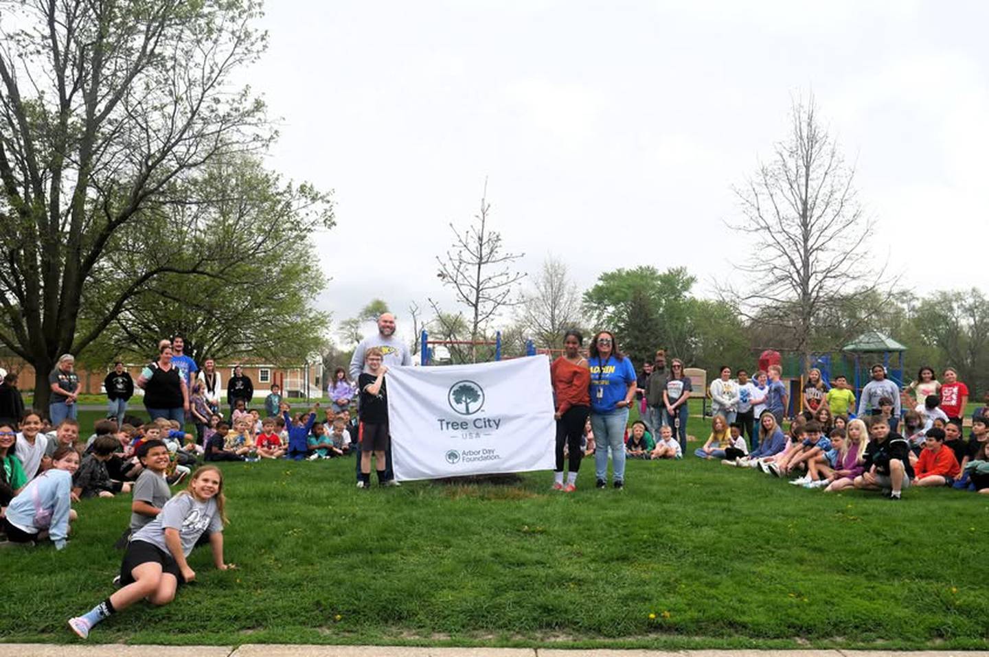 Lincoln Elementary School students gather around the tree planted on Friday near their playground to celebrate Arbor Day on Friday, April 24, 2026, in DeKalb.