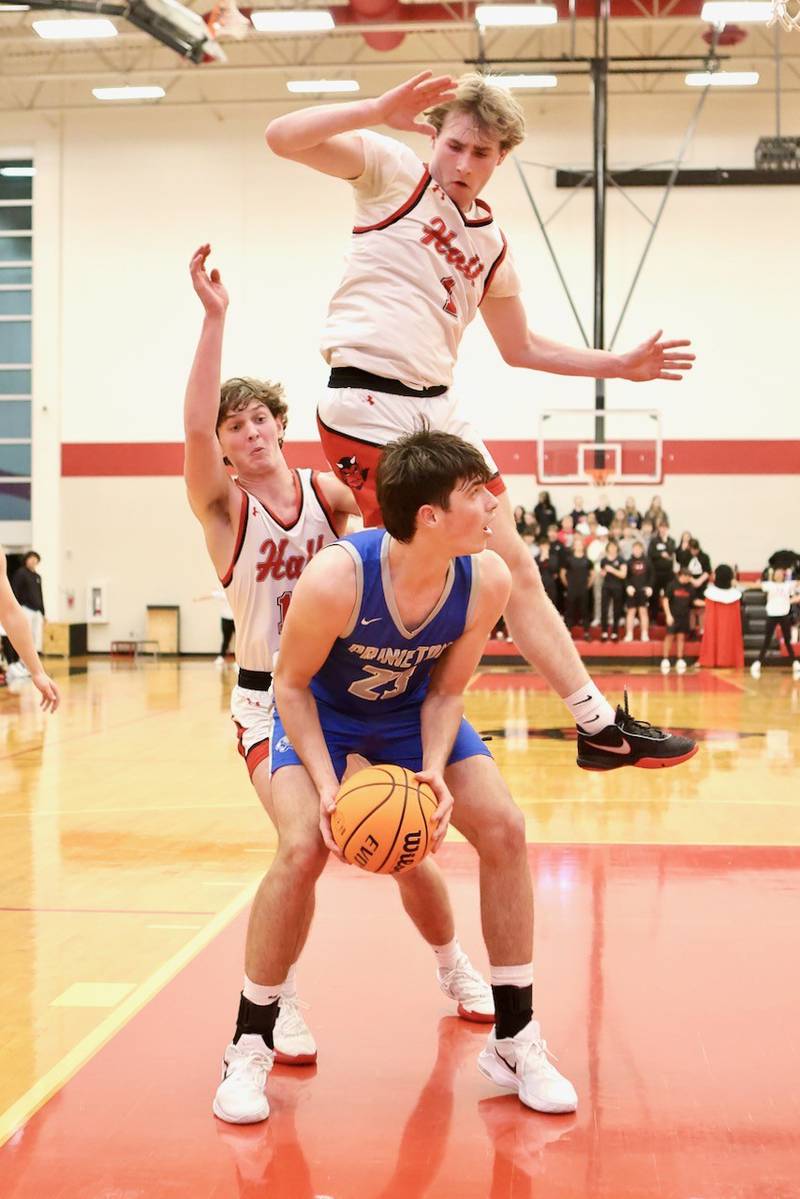 Hall's Wyatt West goes airborne as Princeton's Noah LaPorte pump fakes in the lane Friday night at Hall High School. The Red Devils won 62-54.
