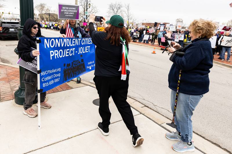 Attendees stop to photograph signs during the Hands Off protest on April 5, 2025.