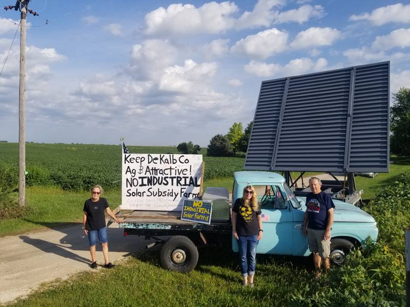 Clare residents opposing possible incoming industrial solar power projects in DeKalb County pose near a full scale model of proposed 15-foot tall solar panels ahead of a Thursday, Aug. 26, 2021 continued public hearing for a project from Texas-headquartered Leeward Energy.