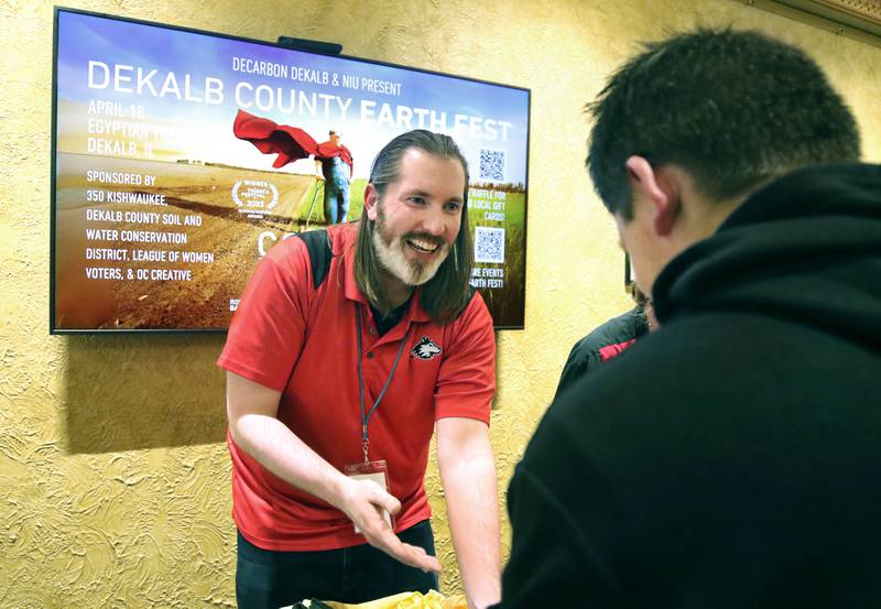 Russ Devereaux, (left) from Northern Illinois University STEAM, helps Marcos Zaylik make jewelry using upcycled T-shirts Thursday, April 18, 2024, during Earth Fest at the Egyptian Theatre in DeKalb. The event, in honor of Earth Week, was presented by DeCarbon DeKalb, in partnership with NIU.