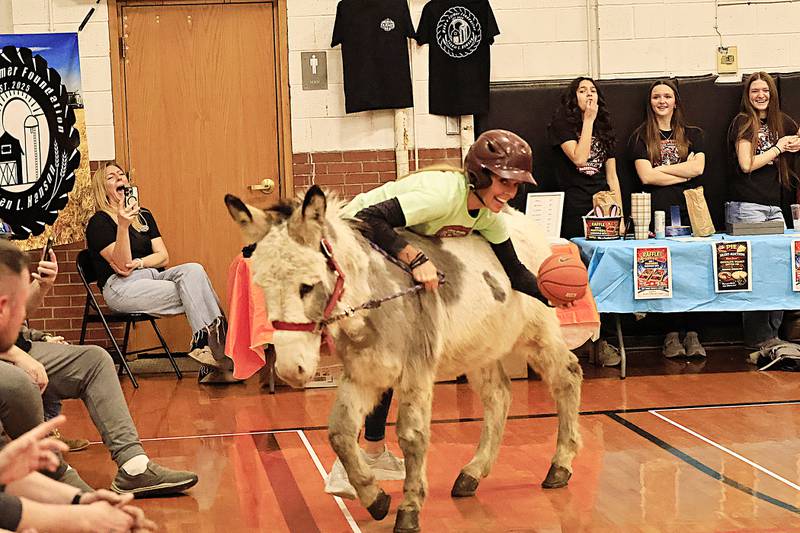 Angie Schroeder tried to climb on her donkey, Elvis, so she could shoot the ball on Friday, March 13, 2026, during the Donkey Ball fun.
