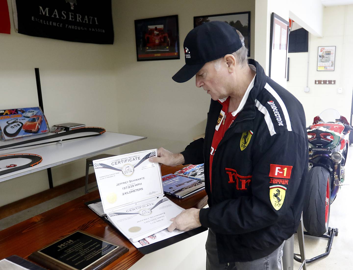 Jeff Schwartz leafs through a binder containing all of the land speed records that he set last year with his Ducati motorcycle and Ferrari at his garage in McCullom Lake on Tuesday, Dec. 27, 2022.