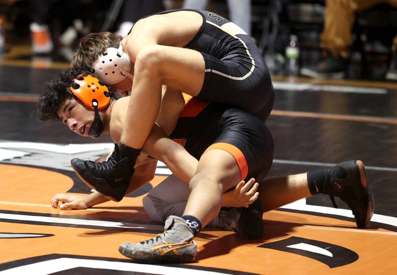Sycamore’s Charlie Olson (top) wrestles DeKalb’s Julian Hartwig Friday, Jan. 17, 2025, during their 113 pound match at DeKalb High School.