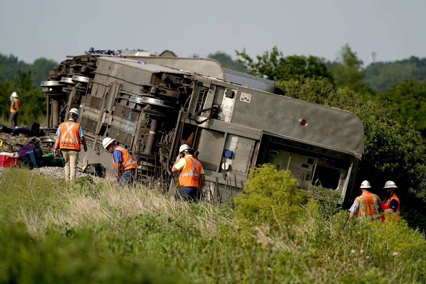 Workers inspect the scene of an Amtrak train which derailed after striking a dump truck Monday, June 27, 2022, near Mendon, Mo. (AP Photo/Charlie Riedel)