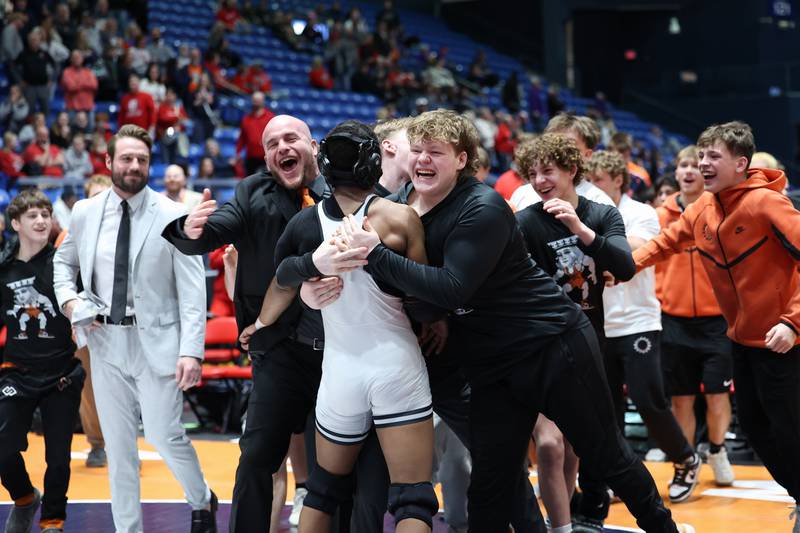 St. Charles East players and coaches rush to celebrate Isaac Lenard's 157-pound match win that secured the IHSA Class 3A Dual Team State third place victory over Oak Park-River Forest on Saturday, Feb. 28, 2026.