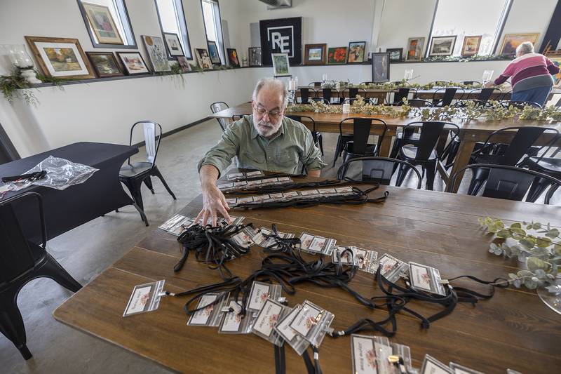 Dick Cholke of Pecatonica lays out name tags for artists Wednesday, April 10, 2024 at Serenity Hospice and Home’s Art Dash fundraiser. Held at the River's Edge Experience in Oregon, the fundraiser features 75 artists and 92 works of art up for grabs by those attending the Wednesday night event.