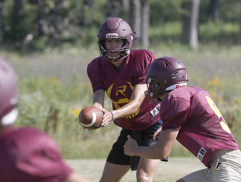 Richmond-Burton’s Joe Miller hands the ball off to Daniel Kalinowski during summer football practice Thursday, July 14, 2022, at Richmond-Burton High School in Richmond.