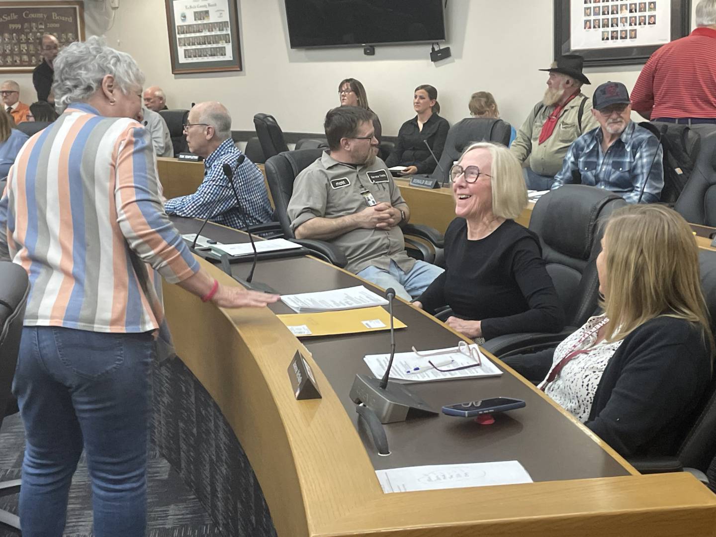 Newly-sworn La Salle County Board member Carol Wiedmann (seated, second from right), an Earlville Republican, shares a laugh with board members Catherine Owens (standing) and Joanne McNally (right). Wiedmann was appointed Thursday, April 9, 2026, to the seat vacated by Kindra Pottinger, who moved out of her district.