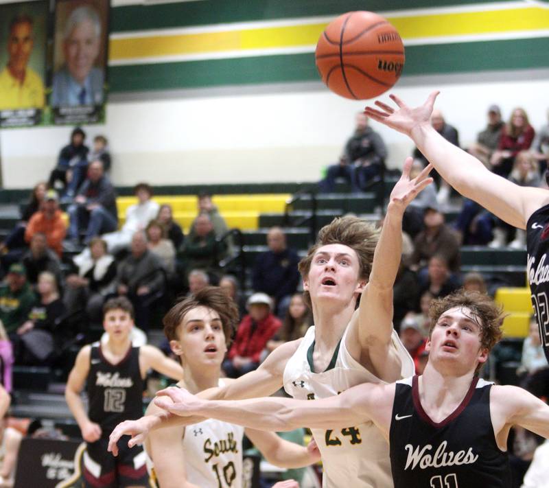 Crystal Lake South’s Cameron Miller (left) and James Carlson battle Prairie Ridge’s James Muse for the ball in varsity boys basketball at Crystal Lake South Friday night.