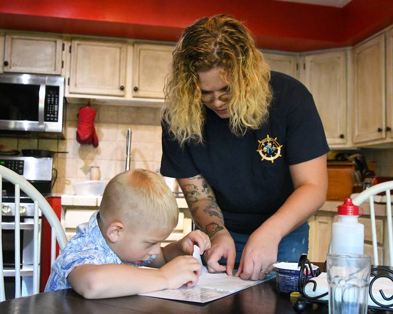 Brooke Christenson helps her son Malcom, 5, tape down paper so he can trace different continents while home schooling her kids on Friday Oct. 3, 2025, in St. Charles Township.
