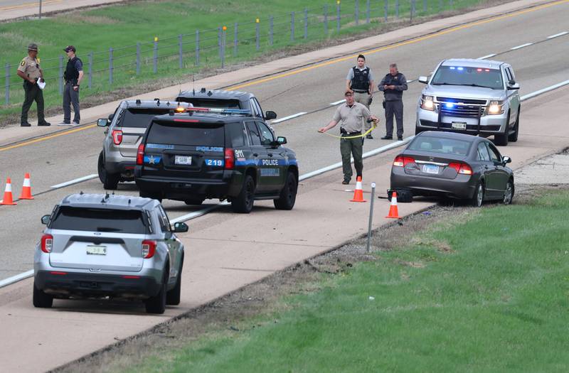 Law enforcement officials work near a Honda sedan with a shattered window in the westbound lanes of Interstate 88 Monday, April 27, 2026, as they investigate an incident on I-88 just west of Keslinger Road in Maple Park.