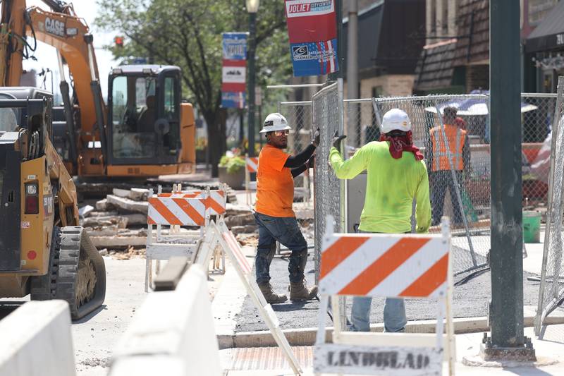 Construction workers put up safety fencing along North Chicago Street in Downtown Joliet on Thursday, Aug. 24, 2023.