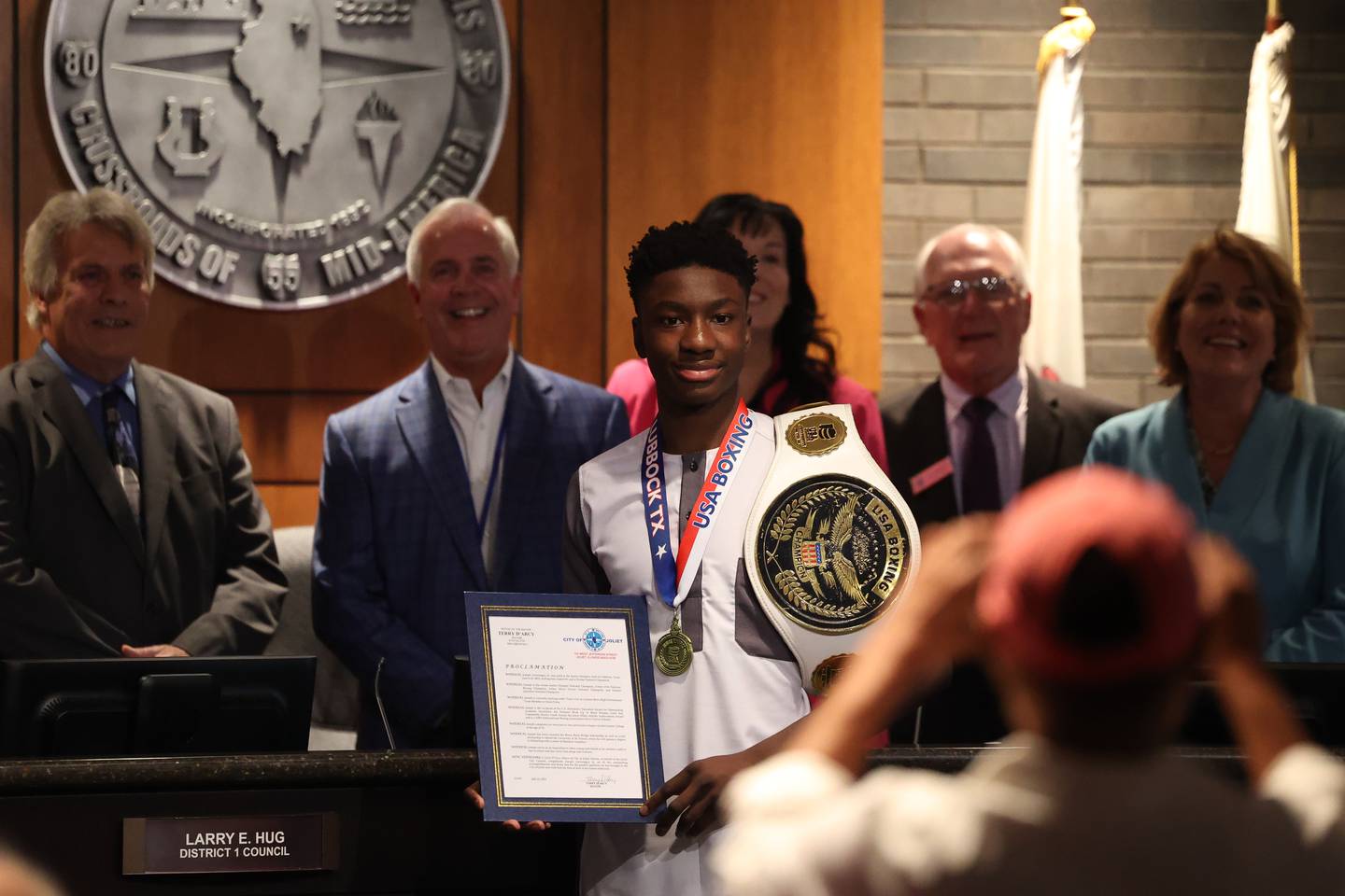 Joseph “JoJo” Awinongya Jr, 4 time Junior Olympics Champion and Joliet native, center, has his photo taken with city council members at the Joliet City Council meeting on Tuesday, July 18th, 2023.