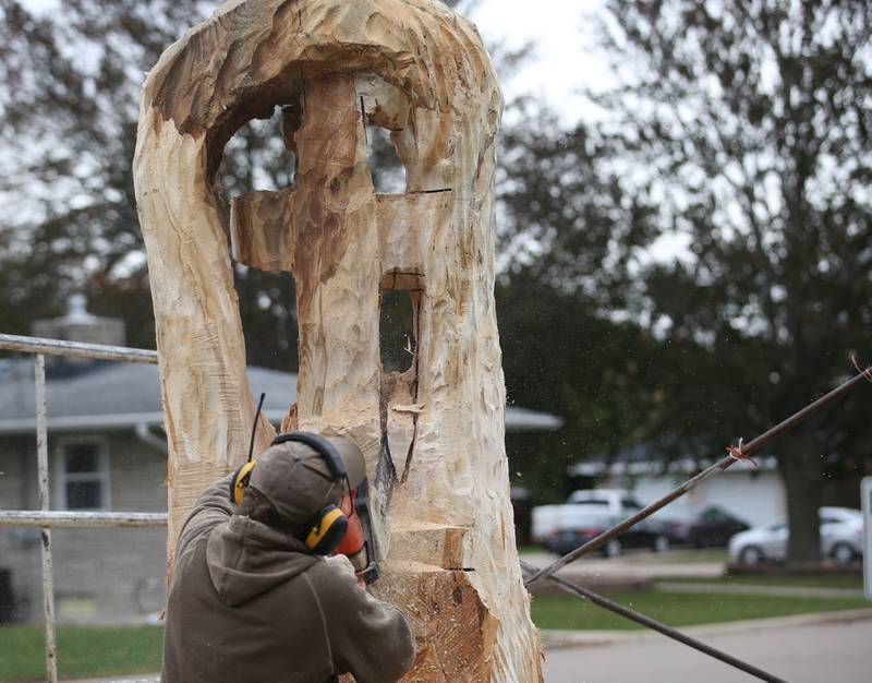 Bud Hainzinger of Morris carves a cross in a tree stump at St. Johns Lutheran Church on Friday, Nov. 3, 2023 in Peru.
