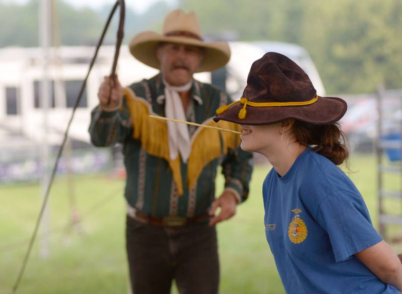 Lily Hackbarth, 15, of Oregon, volunteered to have The Rhinestone Roper snap off a strand of straw as she held it in her mouth during a performance at the Ogle County Fair in Oregon on Thursday, July 31, 2025. Lily is a member of the Byron FFA.