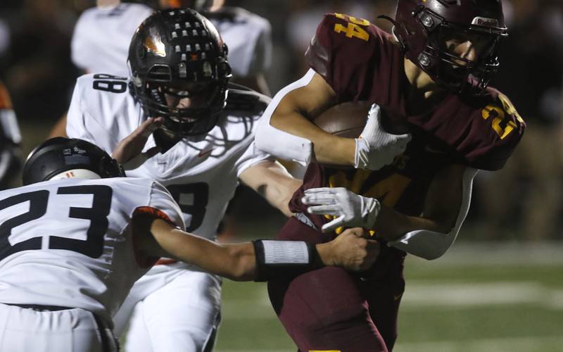 Richmond-Burton's Hunter Carley (right) runs through the tackle attempt of Sandwich's Nate Hill (left)  and Jeffrey Ashley (center) during a Kishwaukee River Conference football game on Friday, Oct. 4, 2024, at Richmond-Burton High School.